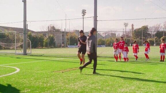 教练向女子足球或足球队队员展示如何在足球或足球场上进行敏捷性和快速跑训练