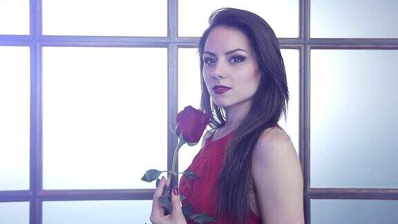 迷人的黑发女孩手里拿着一朵红玫瑰