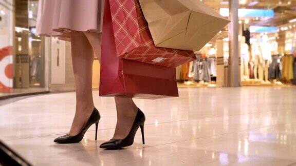 年轻女孩的腿在商场购物她看着橱窗拿着包购物概念时尚概念