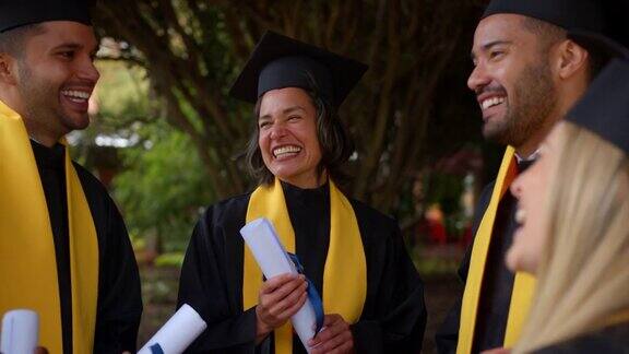 快乐的成年朋友们穿着毕业礼服谈笑风生地从他们的博士项目毕业