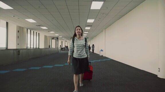 带着红色行李的女旅客走过机场航站楼
