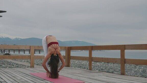 女瑜伽教练正在展示姿势站在海边的外面