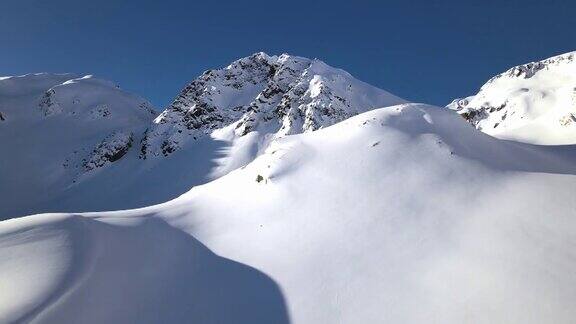在一个晴朗的日子里无人机拍摄的镜头正朝着积雪覆盖的山脉移动