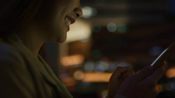 年轻的亚洲女性在晚上用手机发短信