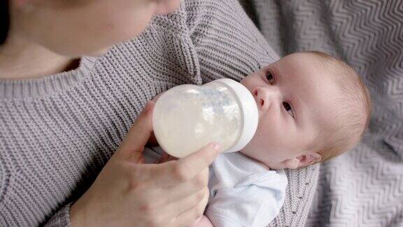 年轻的母亲用奶瓶喂她的婴儿