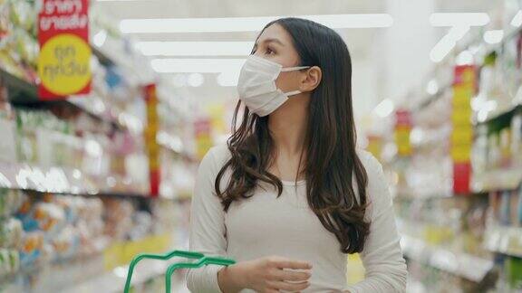 戴着口罩的女人在超市购物和检查食品货架