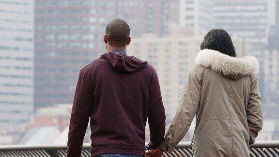在纽约对面的布鲁克林大桥公园里一对夫妇在暴雨过后手牵手走在水边