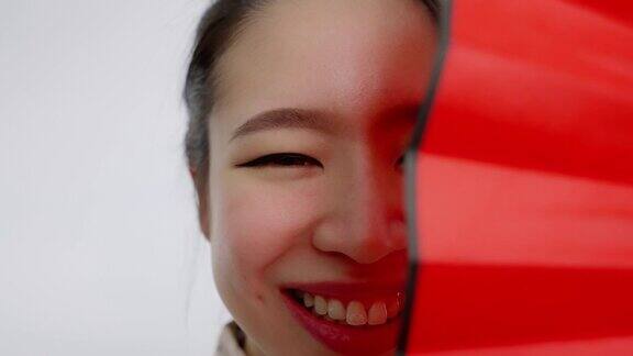 中国亚洲美女春节脸部特写红色扇子遮住了她的左半边脸微笑着看着镜头