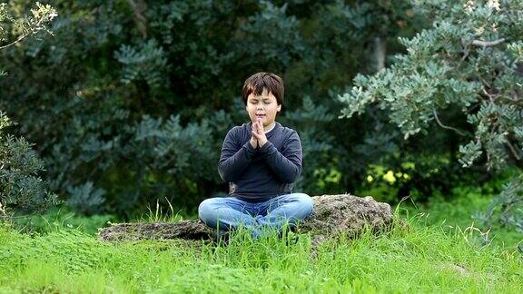 小男孩在户外祈祷和冥想