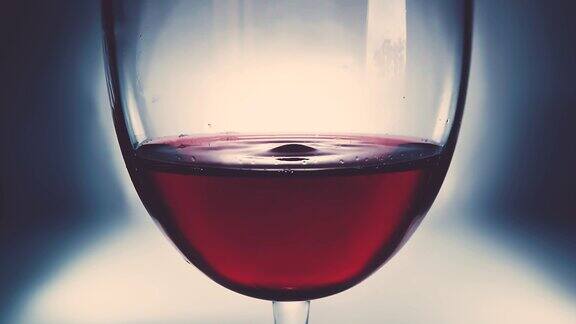 创意微距慢动作视频红酒在玻璃杯和一滴一滴的葡萄酒一个杯子与一个缓慢下降的葡萄酒滴特写旧的复古风格与愉快的软褪色