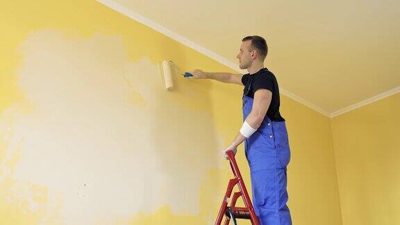 年轻的油漆工正在装修房子英俊的工人正在粉刷新墙