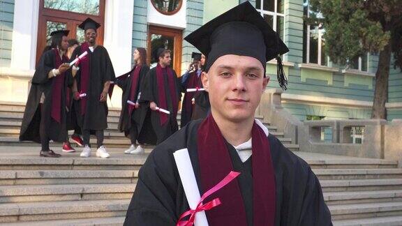 一个男学生拿着学位站在大学台阶上