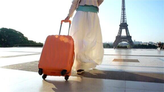 拿着橙色手提箱的女人去巴黎旅行