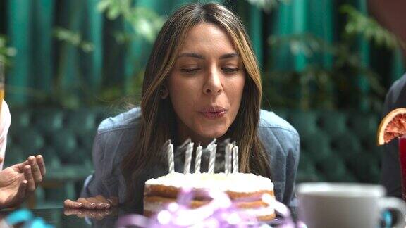 美丽的女人庆祝她的生日吹灭蛋糕上的蜡烛看起来很高兴的特写