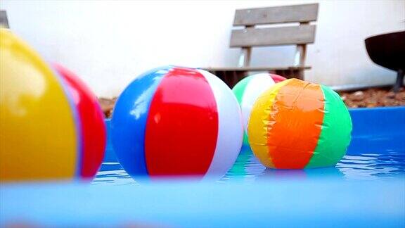 彩色的沙滩球在慢镜头中漂浮在水池中