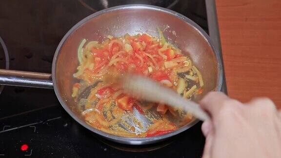 在平底锅里用番茄碎和洋葱煮蕃茄酱厨师用木铲仔细搅拌