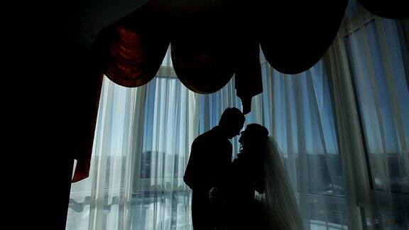 幸福奢华的新娘和新郎站在富丽的房间窗前