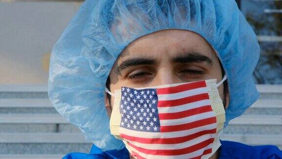 严重过度劳累年轻男性医护人员戴着美国国旗防护面具看着镜头