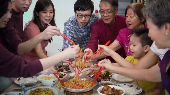 亚洲华人微笑的家庭庆祝除夕夜与生鱼沙拉“渔生”在团圆饭