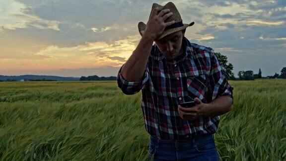一位年轻的农民在田野里行走时使用手机