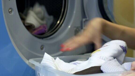 家务妇女小心翼翼地把脏衣服从篮子里放进洗衣机