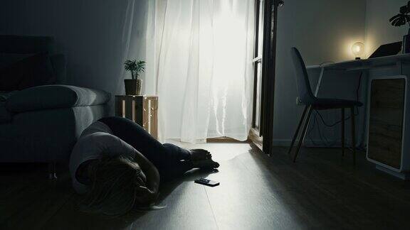 抑郁的女人躺在地板上哭泣