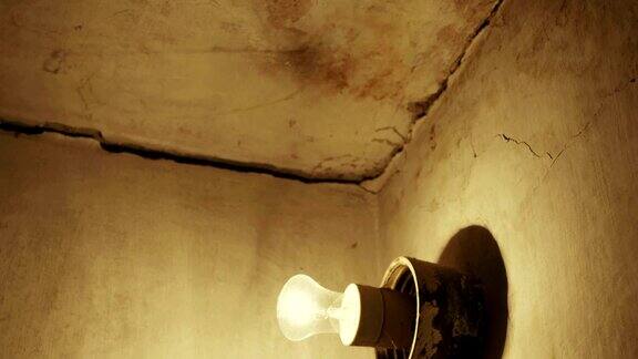 黑暗中开裂的混凝土墙上的旧灯泡在发光