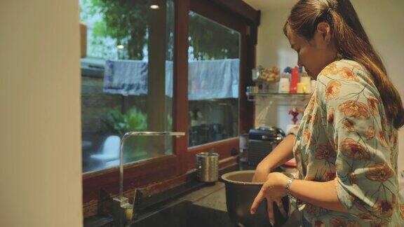 年轻的亚洲人正在家里的厨房里洗电饭锅