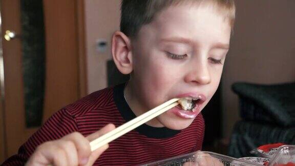 白种学前班男孩愉快地用筷子吃开胃寿司孩子正在吃日本寿司寿司外卖和准备选择性聚焦浅景深