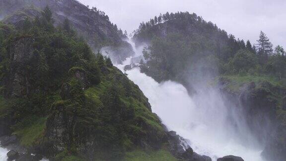挪威多云雨天的拉特福森瀑布周围环绕着绿色的松林在忧郁的日子里水流过峡谷形成薄雾