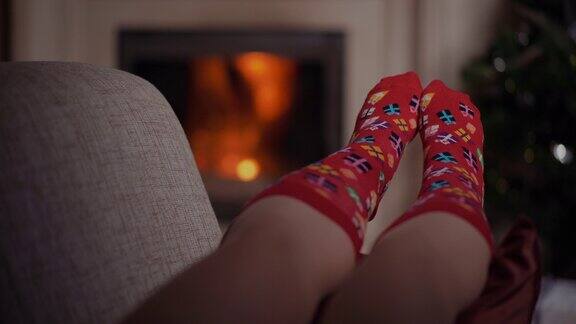 圣诞节时穿着温暖羊毛袜子的女人躺在壁炉旁圣诞节的背景