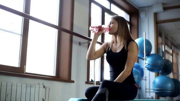 年轻女子在健身房喝水休息