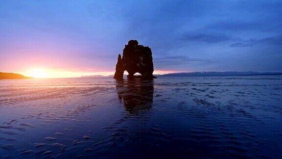 维策库尔是冰岛北部海岸的一块壮观的岩石在这张照片上维察库尔在午夜日落后的海水中倒影