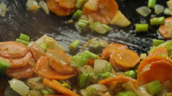芹菜、胡萝卜片和白洋葱在锅上烤的特写