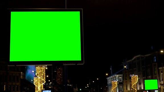两个广告牌大的和小的有一个绿色的屏幕在节日装饰的街道上