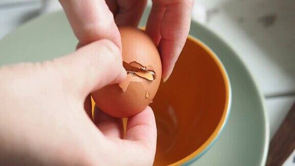 女厨师在碗里打碎一个生鸡蛋做炒鸡蛋做早餐