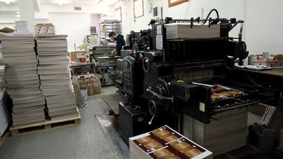 当工人在后台工作时机器在印刷厂对印刷材料进行分类
