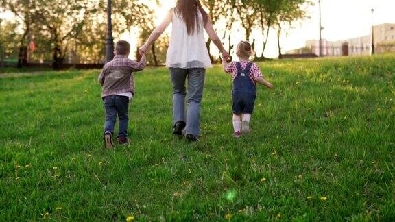 日落时分妈妈和孩子们手牵着手在公园里跑步