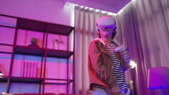 亚洲男孩戴着VR或虚拟现实眼镜头戴式站在家里的电视机前玩视频游戏在隔离期间的技术和创新概念霓虹灯夜的生活方式