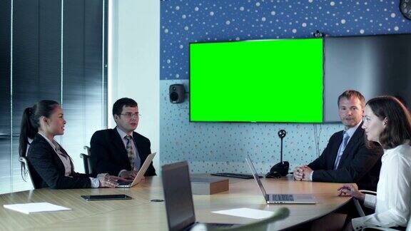 团队员工在会议室交谈墙上的模型用绿屏显示