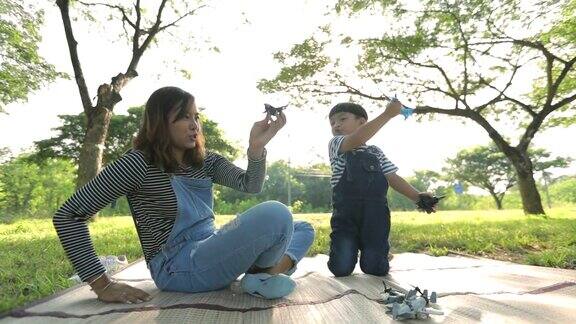 快乐时光妈妈和孩子一起在公园里玩飞机模型慢镜头