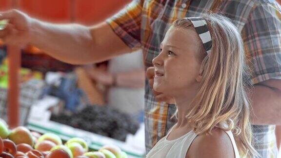 年轻女孩在市场摊位上挑选农产品