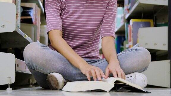 亚洲大学生坐在图书馆的地板上看书
