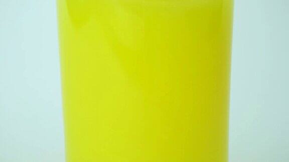 在白色背景的透明玻璃中倒入桔黄色的缓慢过程