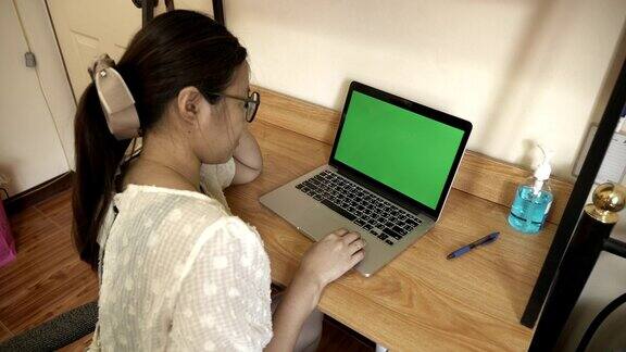 亚洲女性在家里使用彩色键盘屏幕笔记本电脑、封锁、在家工作、新冠肺炎或冠状病毒的场景