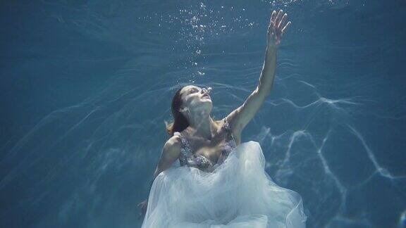 穿着白色裙子的长发女孩漂浮在水下