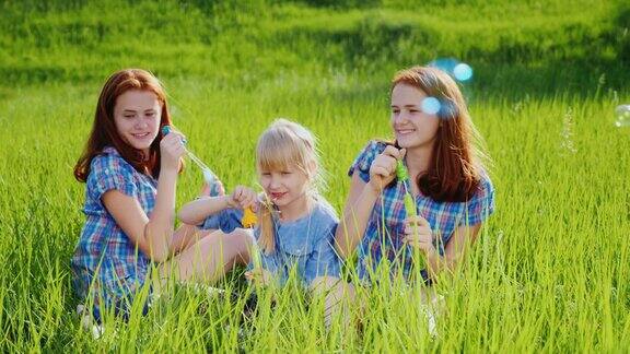 三姐妹在绿色草地上玩肥皂泡一起玩快乐童年
