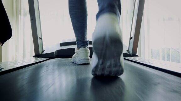 健身女孩走在跑步机上近距离的女人与肌肉腿在健身房