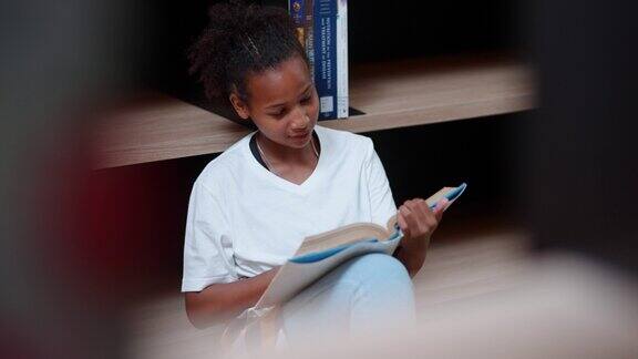 年轻可爱的黑人学生女孩在学校图书馆看书