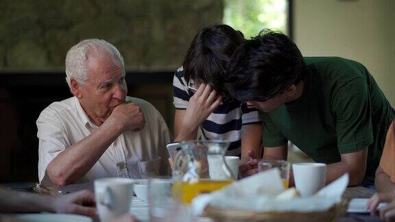 在家庭晚宴上孙子们给爷爷看手机